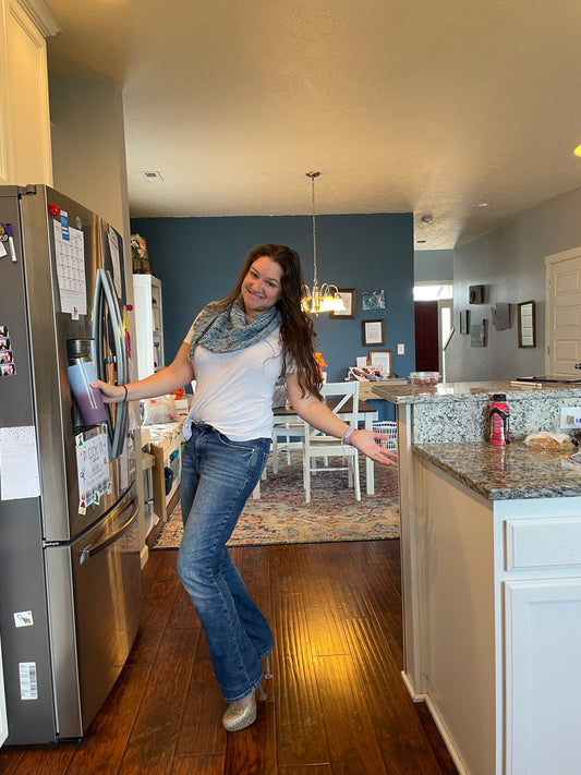 brown haired woman posing next to fridge showing off Imagine When Shawl she knit using the Charles colorway