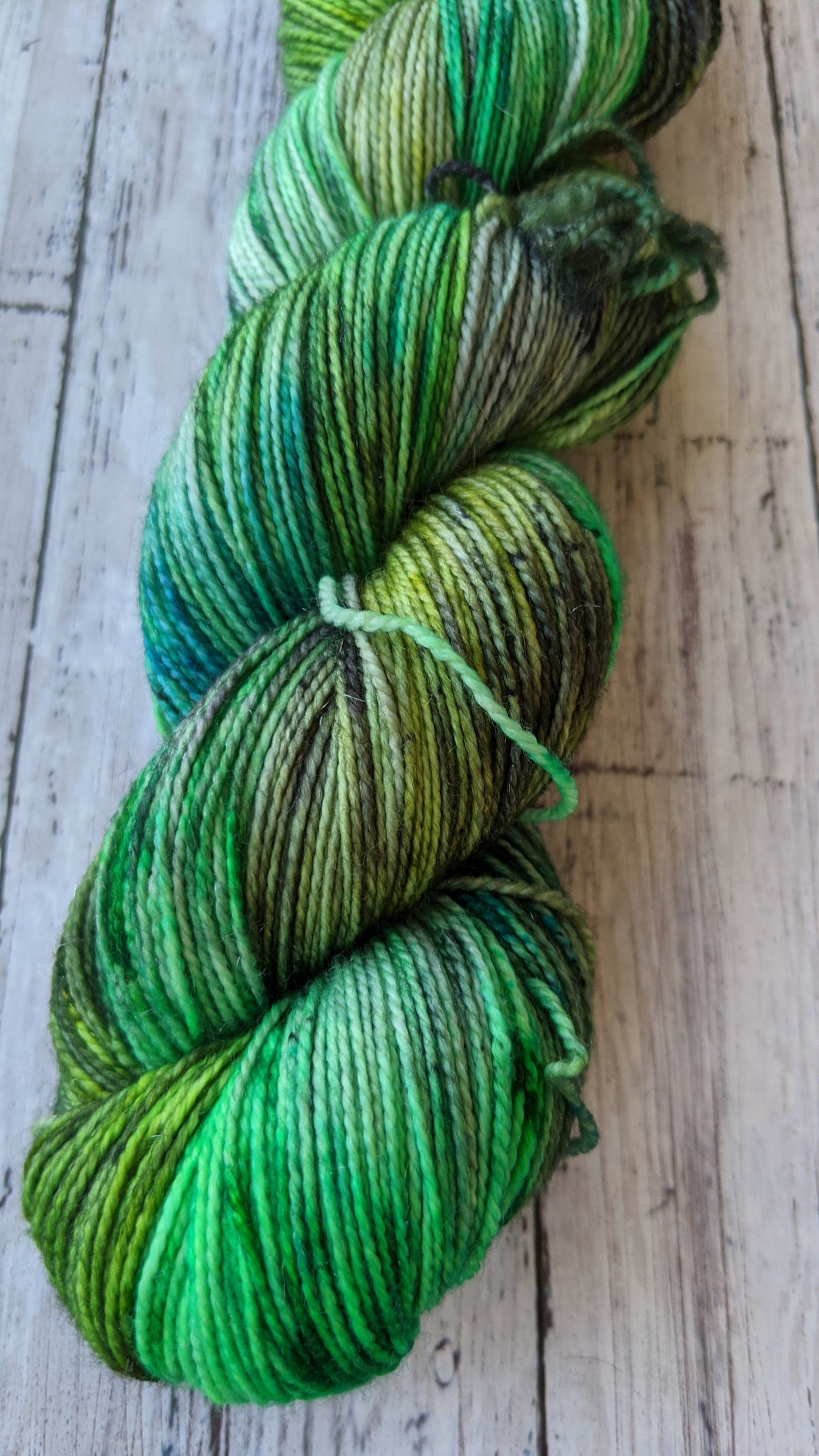 hand dyed various shades of green yarn with black speckles
